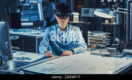 Un ingénieur de développement japonais professionnel travaille dans un micro-casque AR, en travaillant avec des dessins graphiques virtuels dans le laboratoire de recherche de haute technologie Banque D'Images