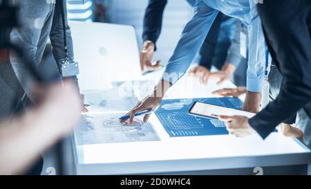 Des ingénieurs, des scientifiques et des développeurs se sont réunis autour de la table de conférence éclairée dans le Centre de recherche technologique, parler, trouver des solutions et Banque D'Images