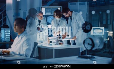 Dans le laboratoire de recherche technologique : équipe diversifiée de scientifiques industriels, ingénieurs, développeurs travailler avec le tableau blanc numérique montrant des photocalques de moteur Banque D'Images