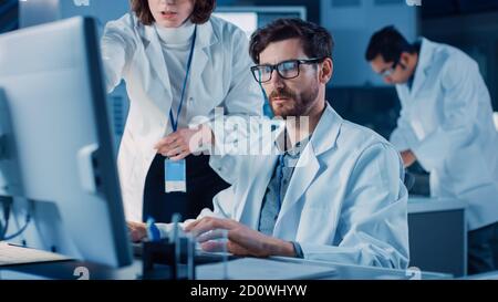 L'ingénieur de développement de moteur de machine travaillant sur l'ordinateur à son bureau, s'entretient avec le chef de projet, montre le composant prototype. Équipe de professionnels Banque D'Images