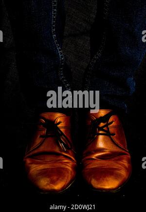 Chaussures en cuir marron cognac sur Jean bleu foncé Banque D'Images