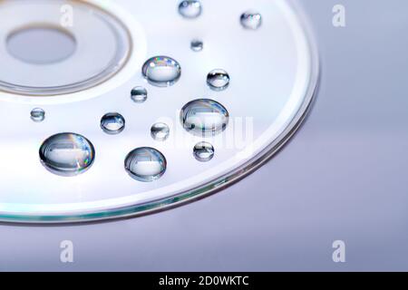 CD contenant des gouttes d'eau - gros plan avec mise au point sélective, arrière-plan futuriste coloré et idée de texture Banque D'Images