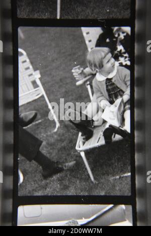 Belle photographie en noir et blanc vintage des années 1970 d'une jeune fille assise sur une chaise de pelouse. Banque D'Images