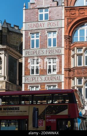 Red bus passant devant un bâtiment annonçant des journaux écossais à Fleet Street, Londres Banque D'Images