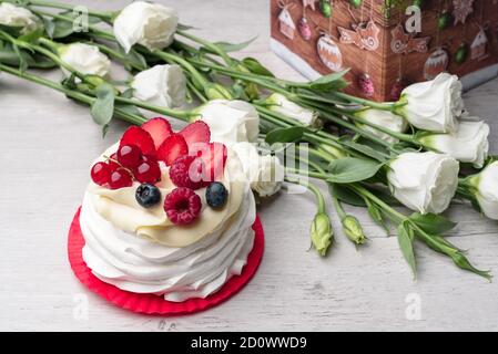 Gâteau à la meringue Pavlova avec crème et framboises, bleuets, fraises, raisins de Corinthe. Boîte cadeau pour le nouvel an Banque D'Images