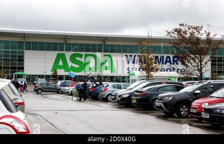 On voit des voitures garées devant une grande Asda et les super-centres de l'ancien propriétaire Walmart.la troisième plus grande chaîne de supermarchés du Royaume-Uni Asda a été vendue par son propriétaire américain Walmart.les frères milliardaires Mohsin & Zuber Issa et la société de capital-investissement TDR Capital ont remporté la guerre dans un contrat de 6,8 milliards de livres sterling. Les frères Issa basés à Blackburn possèdent le groupe EG, qu'ils ont construit à partir d'une seule station-service en 2001 sur plus de 6,000 sites dans le monde et un chiffre d'affaires annuel de 20 milliards de livres sterling. Ce sera la première fois qu'Asda est propriétaire britannique depuis plus de 20 ans. Banque D'Images