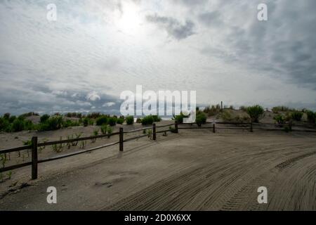 Un ciel orageux derrière une clôture en bois et un sable Dunes sur la plage Banque D'Images