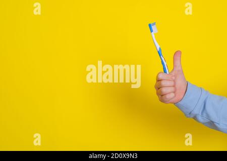 la dent de bébé dans la main d'un enfant. la dentisterie et le concept de santé. Sur fond jaune Banque D'Images