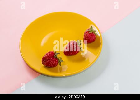 Fraise juteuse mûres lumineux sur une plaque jaune rose pastel sur double-fond bleu. Banque D'Images