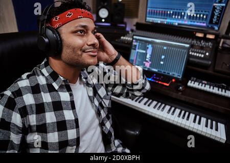 Jeune homme, artiste masculin dans un casque souriant tout en écoutant de la musique dans un studio d'enregistrement Banque D'Images