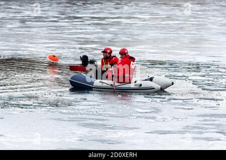 Sofia, Bulgarie - 6 janvier 2020 : des volontaires de la Croix-Rouge bulgare sont vus dans un bateau avant une croix traditionnelle d'Epiphanie qui se jette dans un lac glacé. Banque D'Images