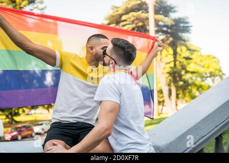 Portrait de jeunes couples gays baisers et montrant leur amour avec le drapeau arc-en-ciel dans la série. LGBT et concept d'amour. Banque D'Images