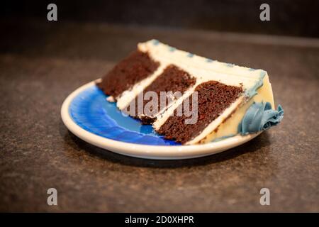 Un riche gâteau trois couches de crème au chocolat humide avec un glaçage épais à la vanille et des rosettes bleu grisâtre de crème au beurre. Banque D'Images