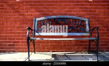 Mur en brique rouge avec banc en fonte à motif fleuri Banque D'Images