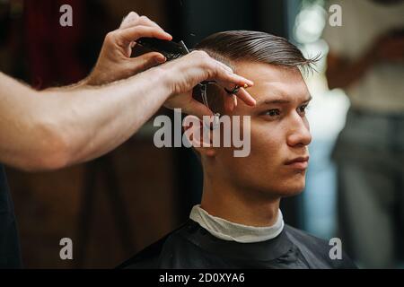 Un jeune homme sérieux et respectueux dans un salon de coiffure Banque D'Images