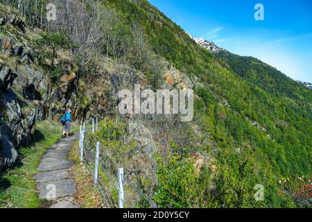 Femme solitaire marcheur, randonneur, sur l'ancien aqueduc qui fournissait de l'énergie aux travaux Auzat Pechiney aluminium, Ariège, France Banque D'Images