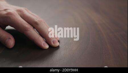 homme à la main vérifiant la surface de la table en noyer ton avec fini huilé, photo large Banque D'Images