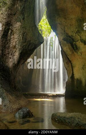 Magnifique cascade secrète Tukad Cepung à Bali, Indonésie. Prise de vue en exposition longue. Des rayons de soleil brillent à travers la montagne au-dessus de la cascade Banque D'Images