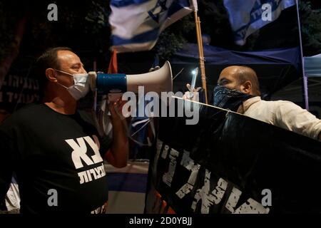 JÉRUSALEM, ISRAËL - OCTOBRE 03 : Un contre-manifestant pro-Netanyahou tient une bannière qui dit « les gauchistes sont des traîtres » alors qu'il affronte un manifestant anti-Netanyahou en utilisant une corne de taureau lors d'une manifestation devant la résidence officielle du Premier ministre malgré un confinement à l'échelle nationale visant à enrayer la pandémie du coronavirus le 03 octobre 2020 à Jérusalem, en Israël. Le Parlement israélien a approuvé la semaine dernière une loi limitant les manifestations dans le cadre d'un état d'urgence lié au coronavirus, qui selon les critiques vise à réduire au silence les protestations contre Netanyahou suite à son inculpation pour corruption Banque D'Images