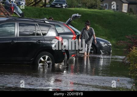 Les résidents de Rothbury, dans le Northumberland, vérifient leurs véhicules après que la rivière Coquet a éclaté sur ses rives. Le week-end humide du Royaume-Uni se poursuivra, car un avertissement météo de pluie a été prolongé dans certaines parties du pays de Galles et de l'Angleterre. Banque D'Images