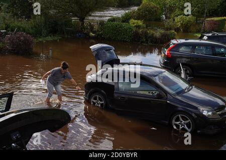 Un résident de Rothbury, dans le Northumberland, jette de l'eau de son véhicule après que le Coquet a fait éclater ses berges. Le week-end humide du Royaume-Uni se poursuivra, car un avertissement météo de pluie a été prolongé dans certaines parties du pays de Galles et de l'Angleterre. Banque D'Images