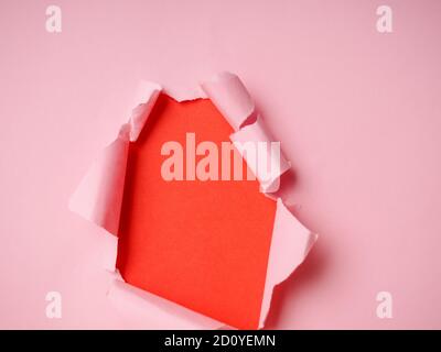 Trou de papier déchiré sur fond rose. Banque D'Images