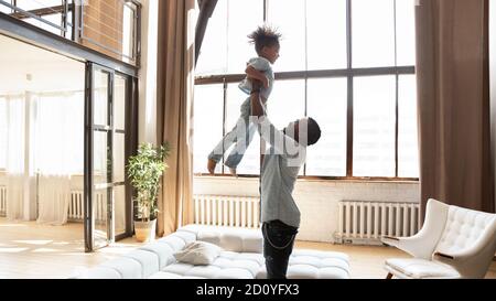 Un jeune homme afro-américain fort élève son enfant dans l'air. Banque D'Images