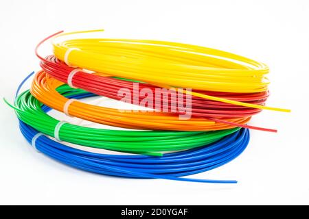 Vue de dessus de quatre marqueurs 3D à filament roulé colorés PLA isolés sur blanc. Gros plan de fils en plastique lumineux pour imprimante 3D en intérieur. Concept de ch Banque D'Images
