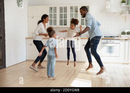 Un couple afro-américain plein de joie sautant avec des enfants énergiques et joyeux. Banque D'Images