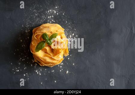 Pâtes italiennes. Pamppardelle curly pâtes sur fond sombre. Vue de dessus. Banque D'Images