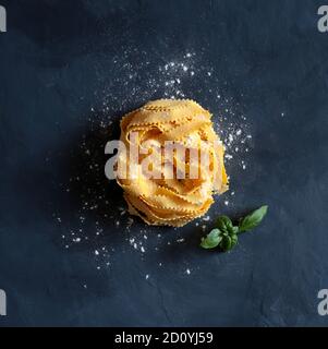 Pâtes italiennes. Pamppardelle curly pâtes sur fond sombre. Vue de dessus. Banque D'Images