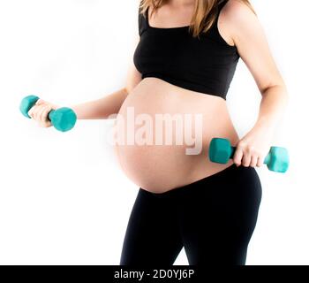 Femme enceinte active en bonne santé s'exerçant avec des haltères, isolée sur fond blanc. Le jeune s'attend à ce que la mère tient bébé dans le ventre de la grossesse. Mater Banque D'Images