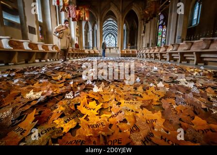 Les gens s'arrêtent pour voir « les feuilles des arbres », un monument créé par l'artiste Peter Walker pour honorer ceux qui sont morts pendant la pandémie du coronavirus, composé de 5,000 feuilles d'acier affichant le mot « espoir », exposé à la cathédrale de Sheffield, dans le South Yorkshire, avant de visiter le pays. Banque D'Images