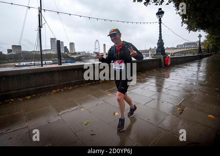 Un coureur portant un numéro de course au marathon de Londres sur l'Embankment, dans le centre de Londres, alors que quelque 45,000 personnes courrent ou marchent le 40ème marathon de Londres sur leur propre itinéraire de 26.2 kilomètres autour du Royaume-Uni, après que l'événement initialement prévu pour avril 26 ait été reporté en raison du coronavirus. Banque D'Images