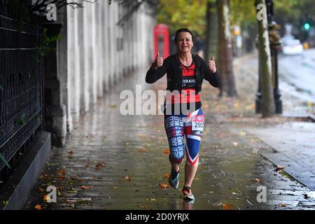 Un coureur portant un numéro de course au marathon de Londres sur l'Embankment, dans le centre de Londres, alors que quelque 45,000 personnes courrent ou marchent le 40ème marathon de Londres sur leur propre itinéraire de 26.2 kilomètres autour du Royaume-Uni, après que l'événement initialement prévu pour avril 26 ait été reporté en raison du coronavirus. Banque D'Images