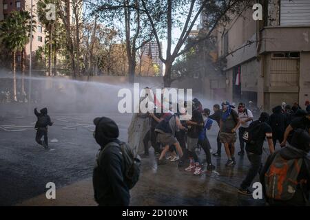 Santiago, Chili. 03ème octobre 2020. Les manifestants se protègent de la laine de la voiture lance des eaux avec des boucliers, pendant la manifestation.des centaines de manifestants affrontent la police à proximité de la Plaza Baquedano, rebaptisée « Plaza de la Digidad » par le peuple pour demander justice pour Antoni, un homme de 16 ans qui a été jeté d'un pont par la police le jour de la manifestation précédente. Crédit : SOPA Images Limited/Alamy Live News Banque D'Images