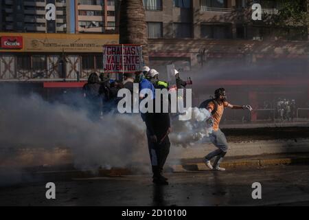 Santiago, Chili. 03ème octobre 2020. Les manifestants retournent des grenades lacrymogènes qui leur sont lancées par la police anti-émeute pendant la manifestation.des centaines de manifestants affrontent la police à proximité de la Plaza Baquedano, rebaptisée « Plaza de la Dignidad » par le peuple pour demander justice à Antoni, un homme de 16 ans qui a été jeté d'un pont par la police le jour de la manifestation précédente. Crédit : SOPA Images Limited/Alamy Live News Banque D'Images