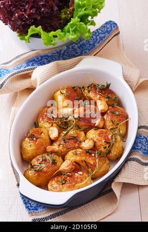 Pommes de terre rôties à l'ail, au thym et au romarin dans un plat de cuisson en céramique Banque D'Images