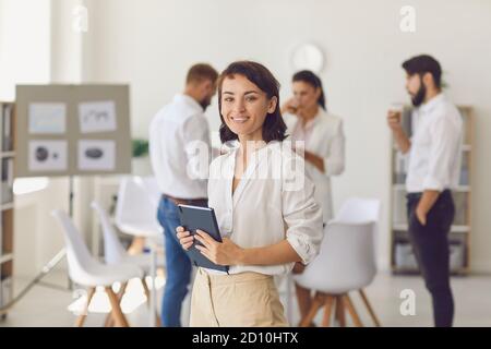 Bonne femme d'affaires ou chef d'entreprise à la recherche d'un bureau à l'appareil photo et souriant Banque D'Images