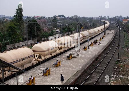 Bhubaneswar, Inde - 4 février 2020 : un train de marchandises passe dans la ville alors que les gens attendent sur les bancs à la gare le 4 février 2020 Banque D'Images