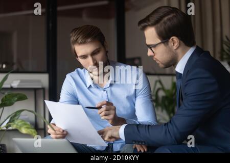 Un jeune employé focalisé discutant du document papier avec le directeur général. Banque D'Images