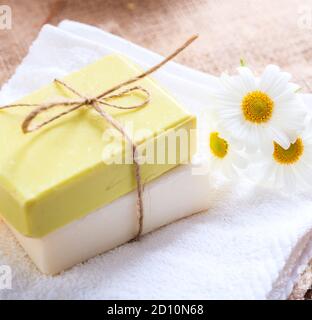 Savons de camomille faits maison. Porte-savon artisanal de couleur blanche et jaune, vue rapprochée. Cosmétiques naturels et sains à base de plantes Banque D'Images