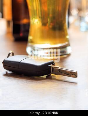 Boire et conduire, dui concept. Clé de voiture sur un comptoir de pub, arrière-plan de verres à bière, vue rapprochée Banque D'Images