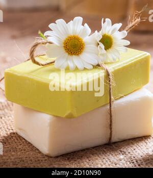 Savons de camomille faits maison. Porte-savon artisanal de couleur blanche et jaune, vue rapprochée. Cosmétiques naturels et sains à base de plantes Banque D'Images