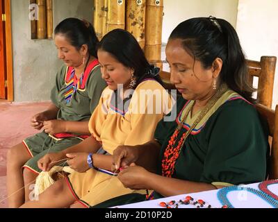 Nueva Loja, Sucumbios / Equateur - 2 septembre 2020: Groupe de trois femmes autochtones de nationalité cofan qui tissage de l'artisanat dans leur maison dans l'AMAZ Banque D'Images