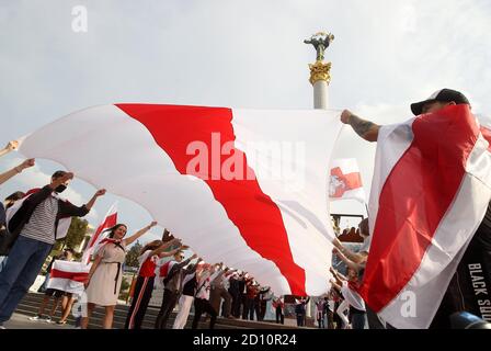 Des manifestants portant un grand drapeau blanc-rouge-blanc historique du Bélarus pendant le rassemblement.des citoyens biélorusses vivant en Ukraine et des militants ukrainiens ont participé à un rassemblement pour exprimer leur solidarité avec le mouvement de protestation en Biélorussie contre les résultats des élections présidentielles. Banque D'Images