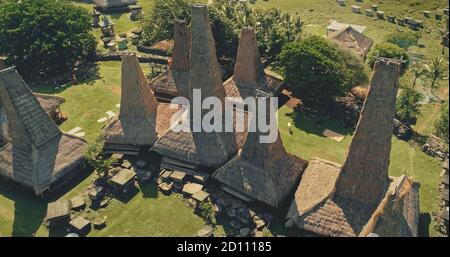 Terres tropicales verdoyantes avec des maisons uniques avec vue aérienne traditionnelle du village. Paysage de verdure sur la nature tropique le jour d'été de l'île de Sumba, Indonésie, Asie au tir de drone oiseau-oeil Banque D'Images