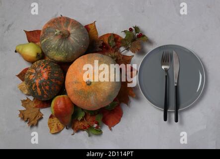 Mise en table le jour de Thanksgiving décoré de citrouille, de viburnum, de poires et de feuilles colorées sur le gris. Vue de dessus Banque D'Images