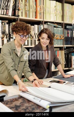 Jeune femme brune assistant de magasin aidant le client à choisir nouveau fonds d'écran Banque D'Images