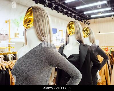 Mannequins féminins abstraits avec visages dorés dans le stand de vêtements de soirée dans la boutique Banque D'Images